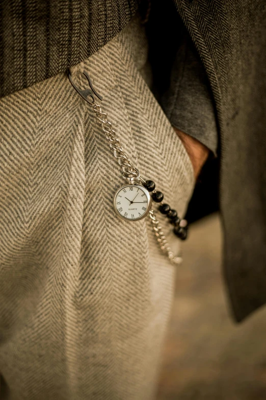 the back end of a man's pants with a silver and black tie with an engraved watch