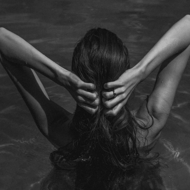 woman with her hands on her head, swimming in the water