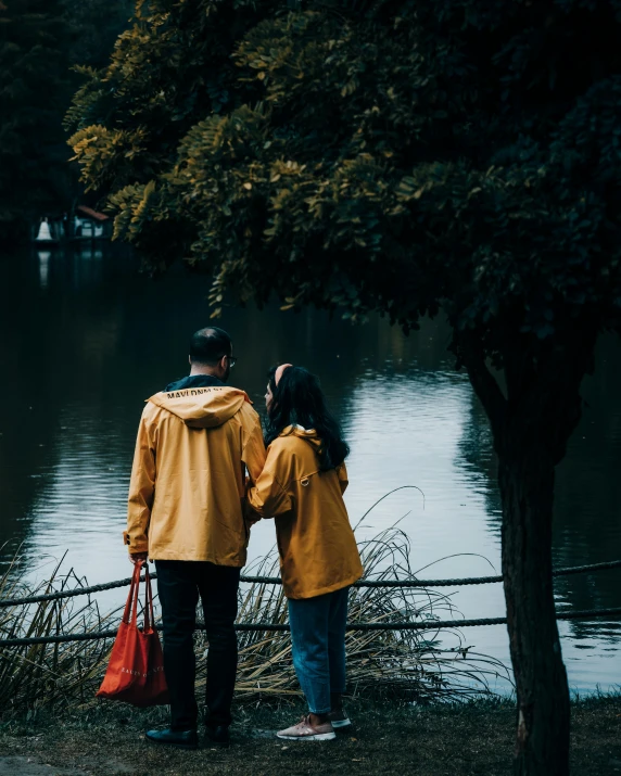 a man and woman are walking in front of a lake