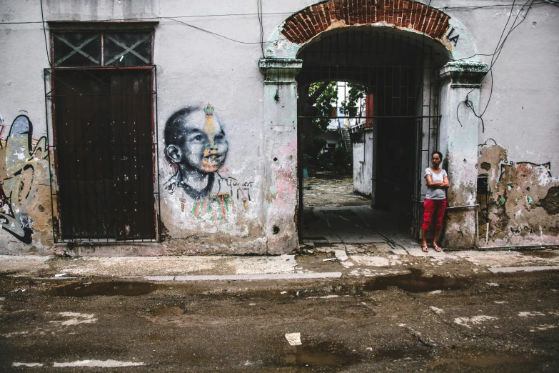 a man stands on the sidewalk near a dilapidated doorway