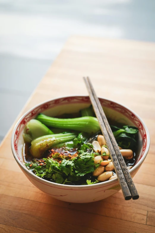 a bowl of soup with broccoli and snap peas with chop sticks