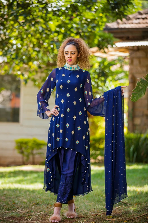 a woman is standing in the grass wearing a blue dress