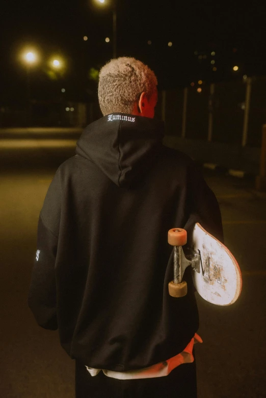 a person wearing a hoodie holding a skateboard