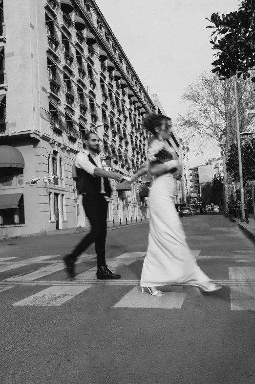 a bride and groom cross a city street