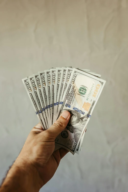 a person holding a handful of money against a white background