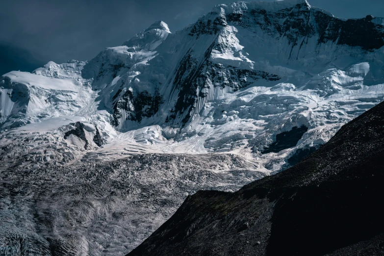 an mountain range covered in snow under a cloudy sky