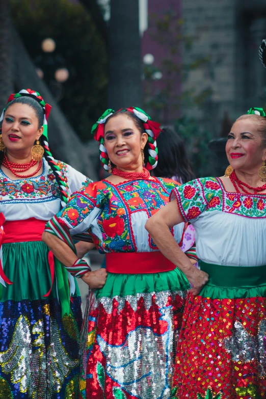 three beautiful women in mexican costumes holding a piece of paper