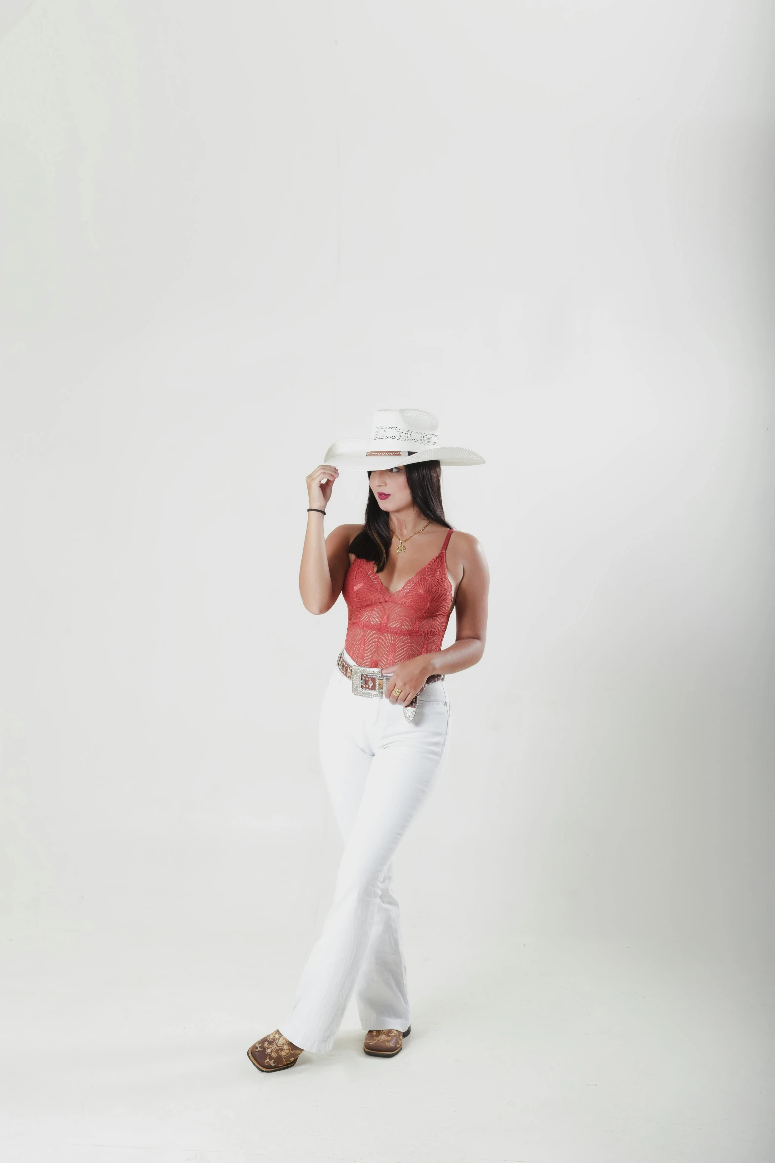 a woman wearing white jeans and a red tank top poses for a pograph