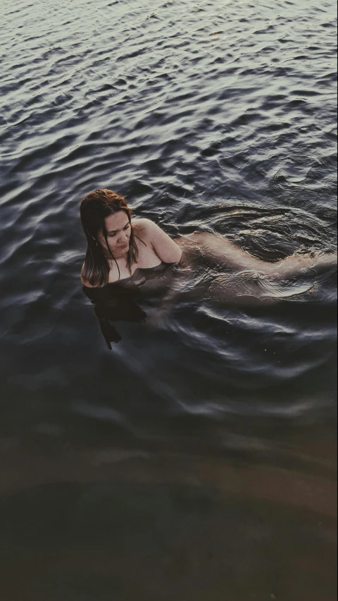 a woman in black bathing suit floating in water