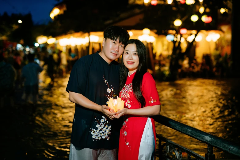 a couple poses together in front of some dark - colored buildings