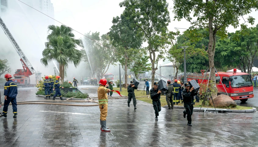 several people standing on the street as the firefighter in yellow and red is doing work on the fire