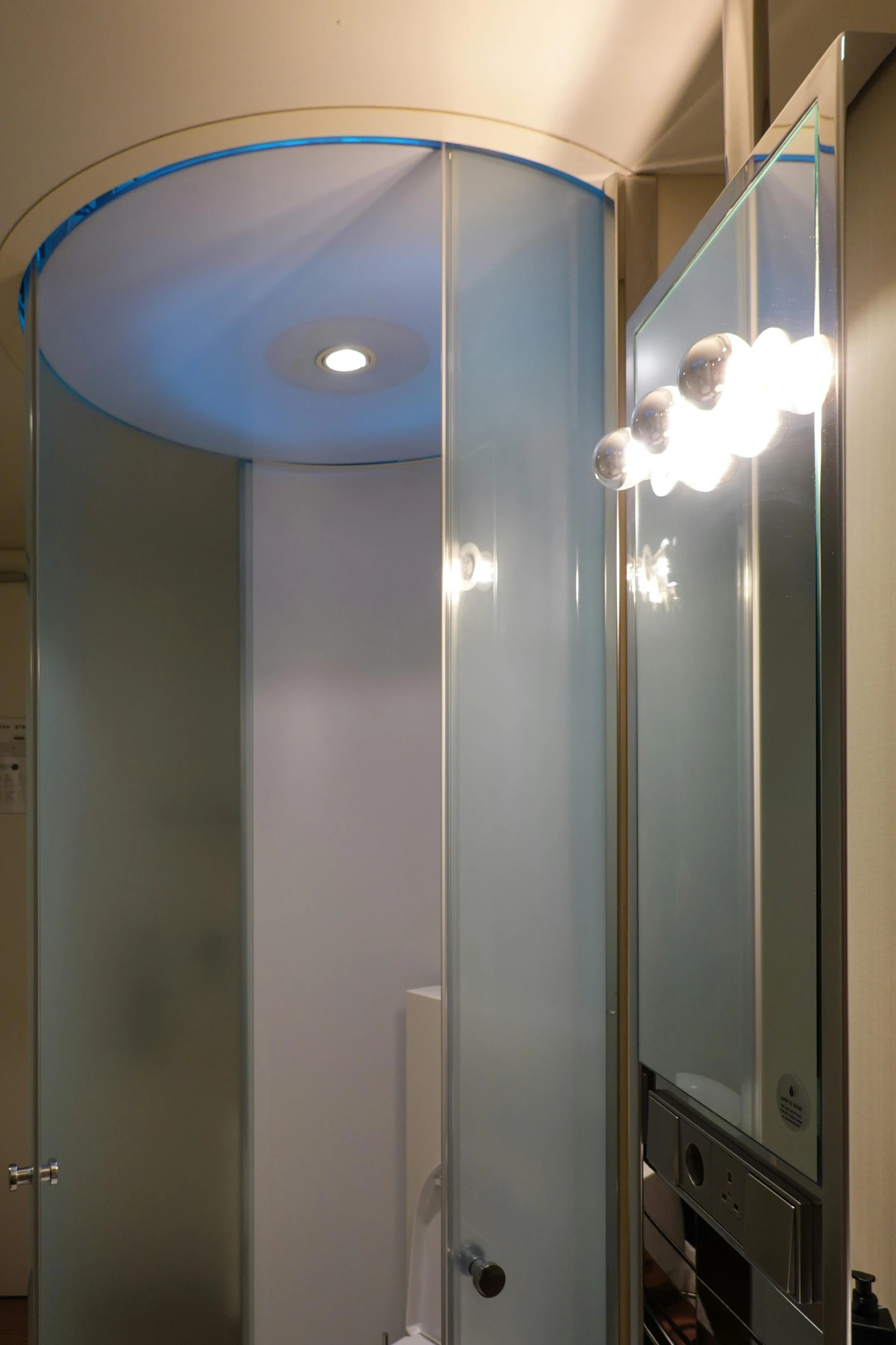 a shower room with a curved glass shower and vanity mirror