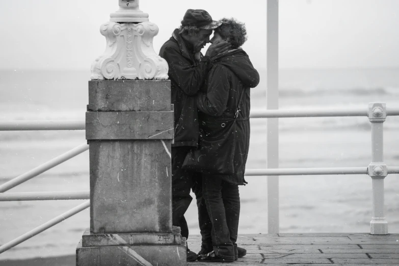 black and white pograph of two men kissing on the pier