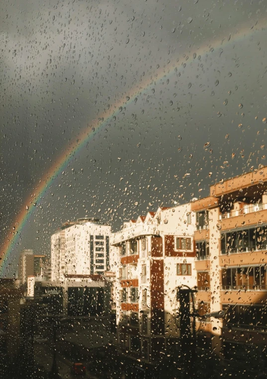 a rainbow in the background from a rain streaked window