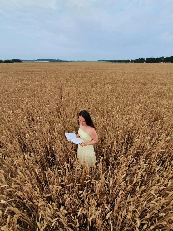 a woman standing in a wheat field while holding soing