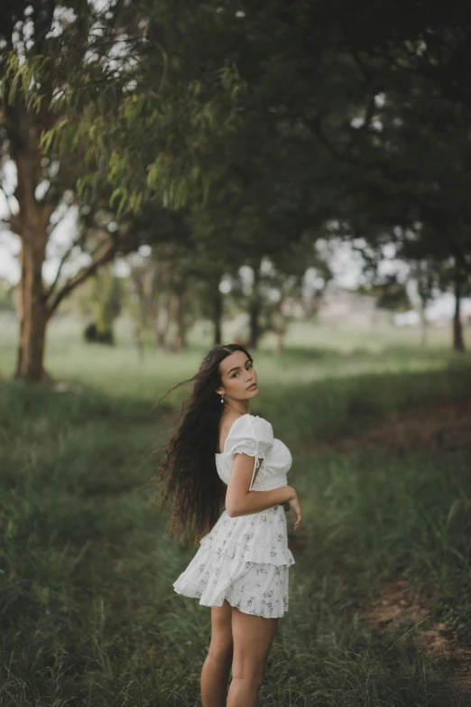 a woman is standing in some grass and looking up