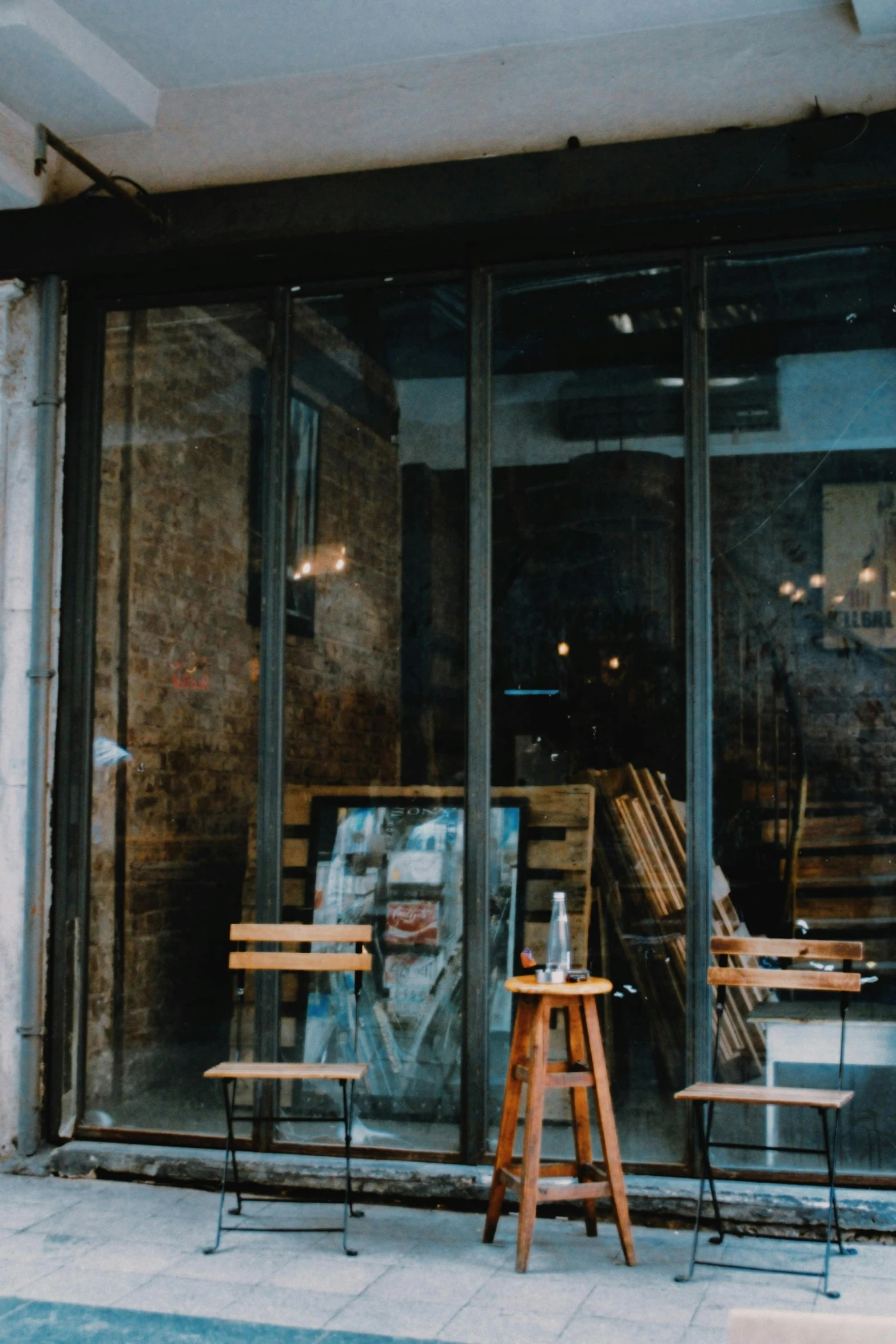 two wooden chairs sitting outside of a glass store window