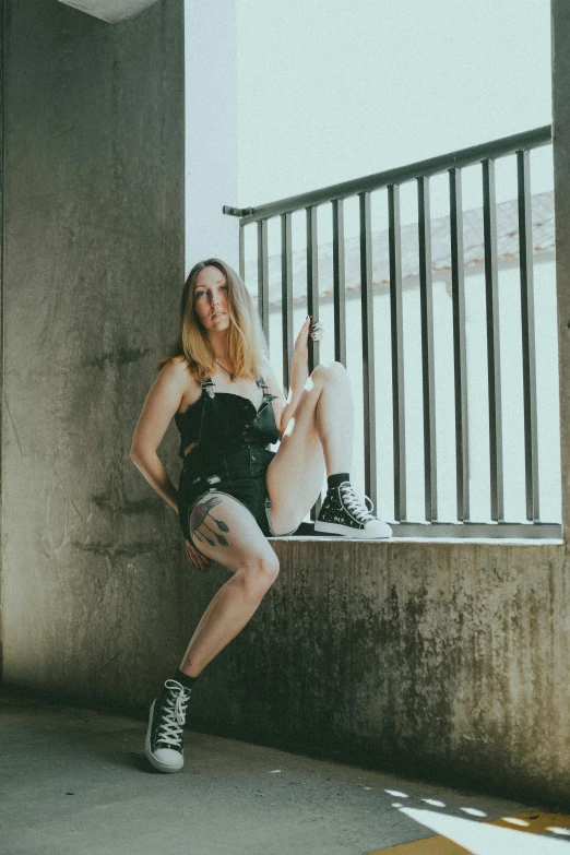 a young woman in black shirt and skirt posing on ledge