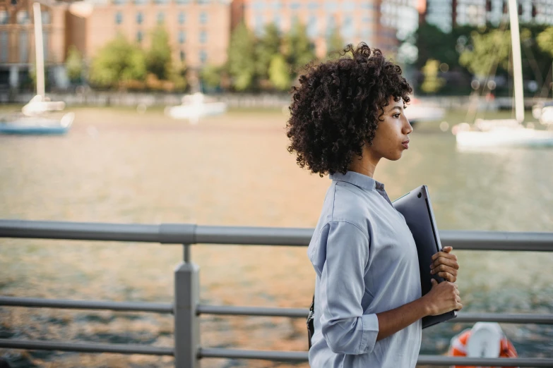 woman walking through a body of water holding a book