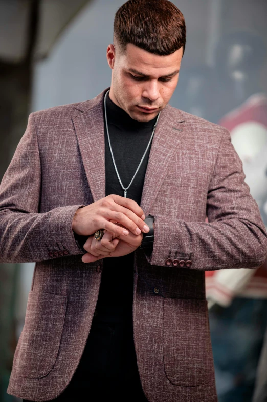 a man wearing a jacket and looking down at his watch