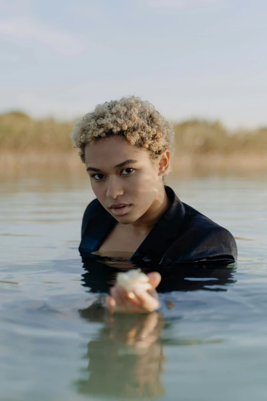 a young woman holding a flower in the water