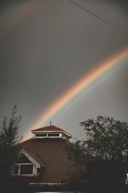 the rainbow is shining brightly above the house