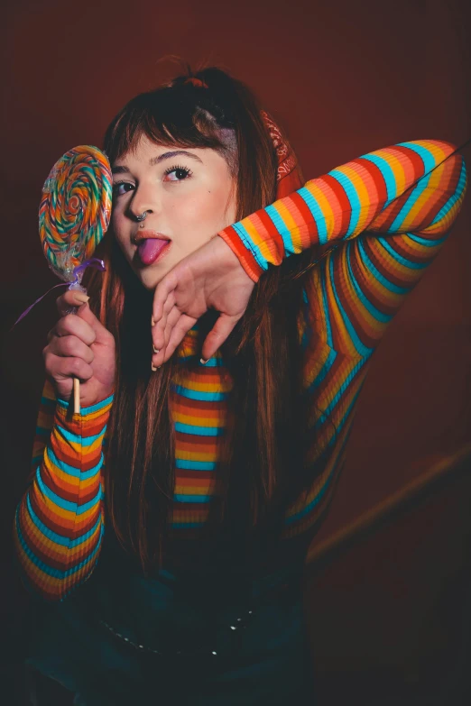 woman with fake tongue sticking out her tongue while holding a lollipop