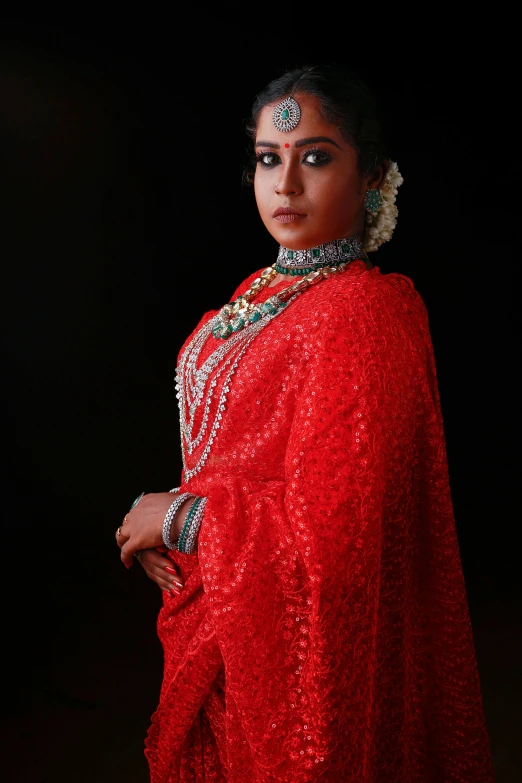 a woman wearing a red, metallic dress with white necklaces and pearls