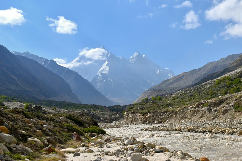 mountains are in the background as rocks and vegetation grow around the river