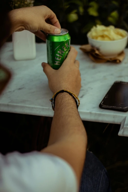 a man is holding a can of soda and looking at his phone