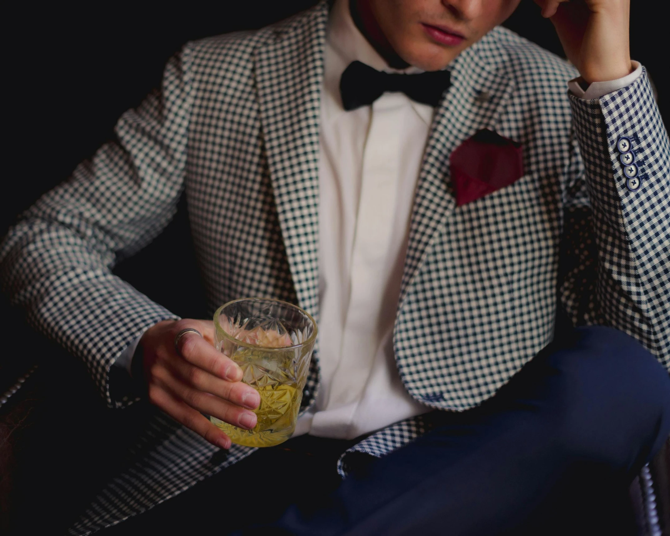 the young man is sitting down holding his drink