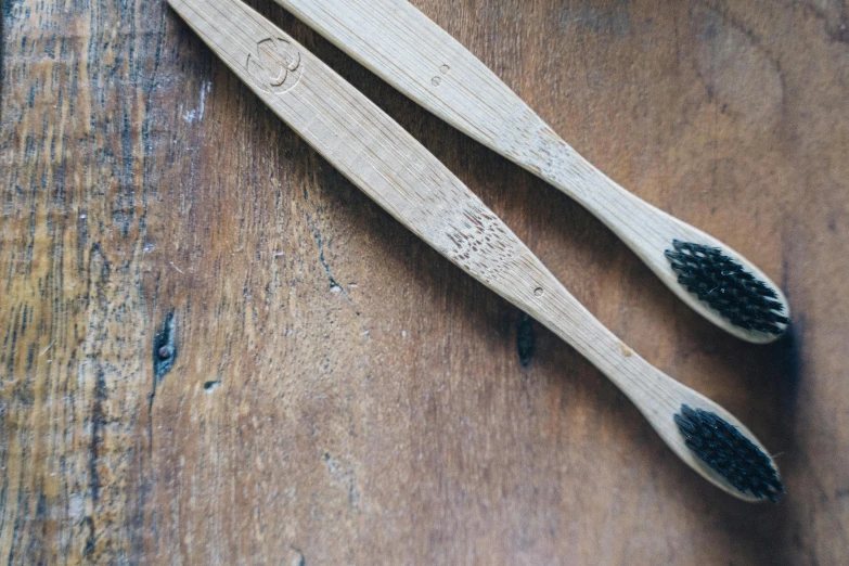 two wooden brushes laying on a wood surface