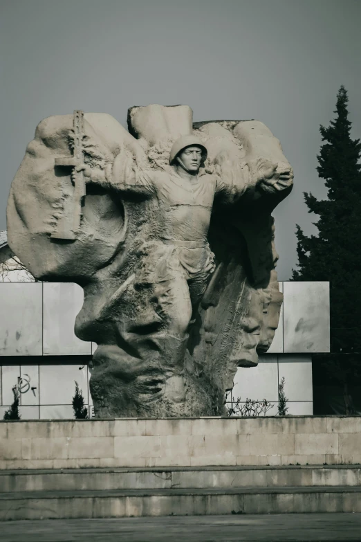 a monument with a statue of a man and other figures next to it