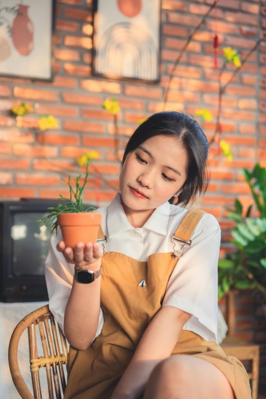 a girl sitting on a chair holding up a potted plant