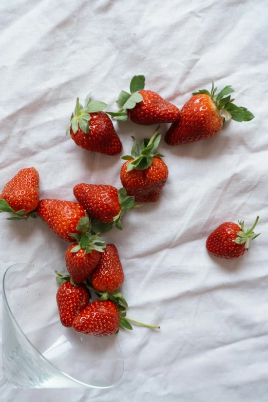 a group of strawberries is lying in a triangular bowl on a sheet