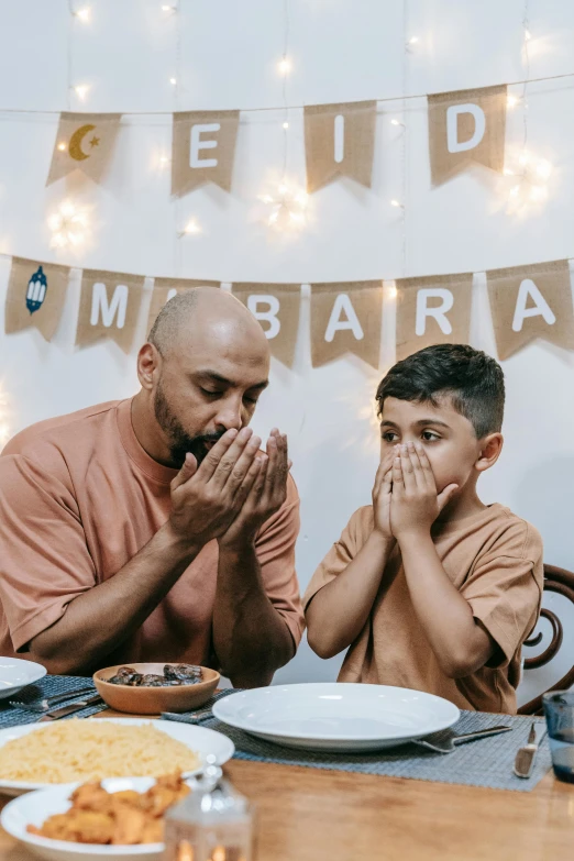 a man and child sitting in front of a table covered with food