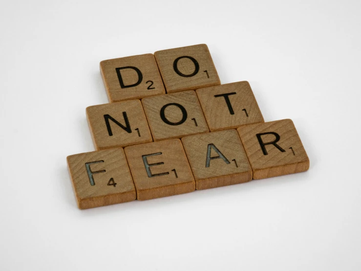 a set of three scrabble tile letters with the words do not fear spelled in black