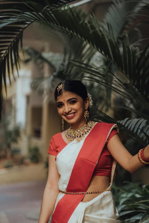 a woman in a white and red saree with matching jewelry