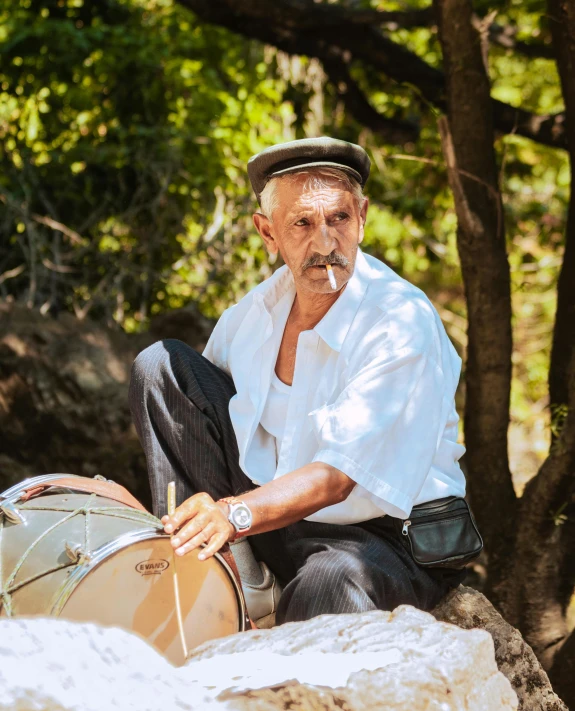 a man wearing a hat sitting next to a piece of luggage