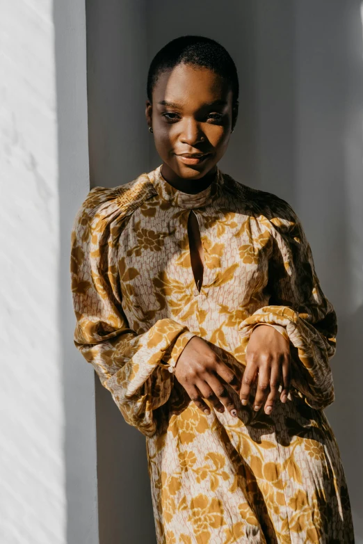 a woman with a yellow patterned dress is standing in a room