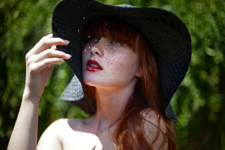 a woman with red hair and makeup wearing a large hat