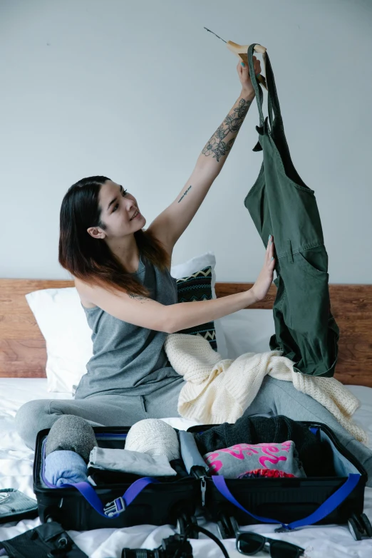 a girl is sitting on her bed with her purse and the hood opened