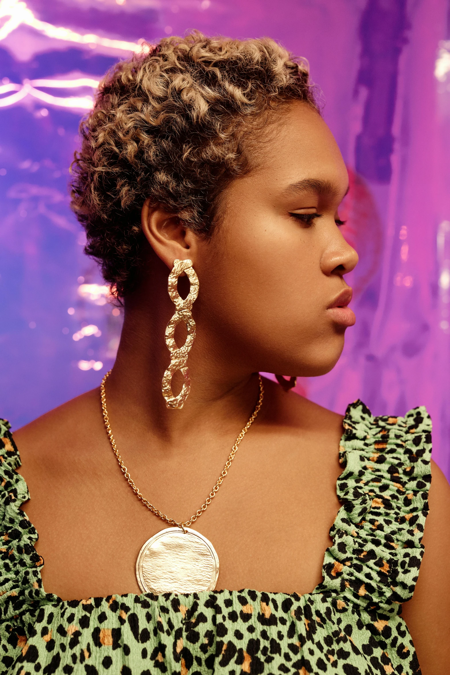 woman with afro hair wearing two different gold circles earrings and necklace