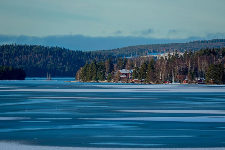 the view across a lake of some houses with hills in the distance