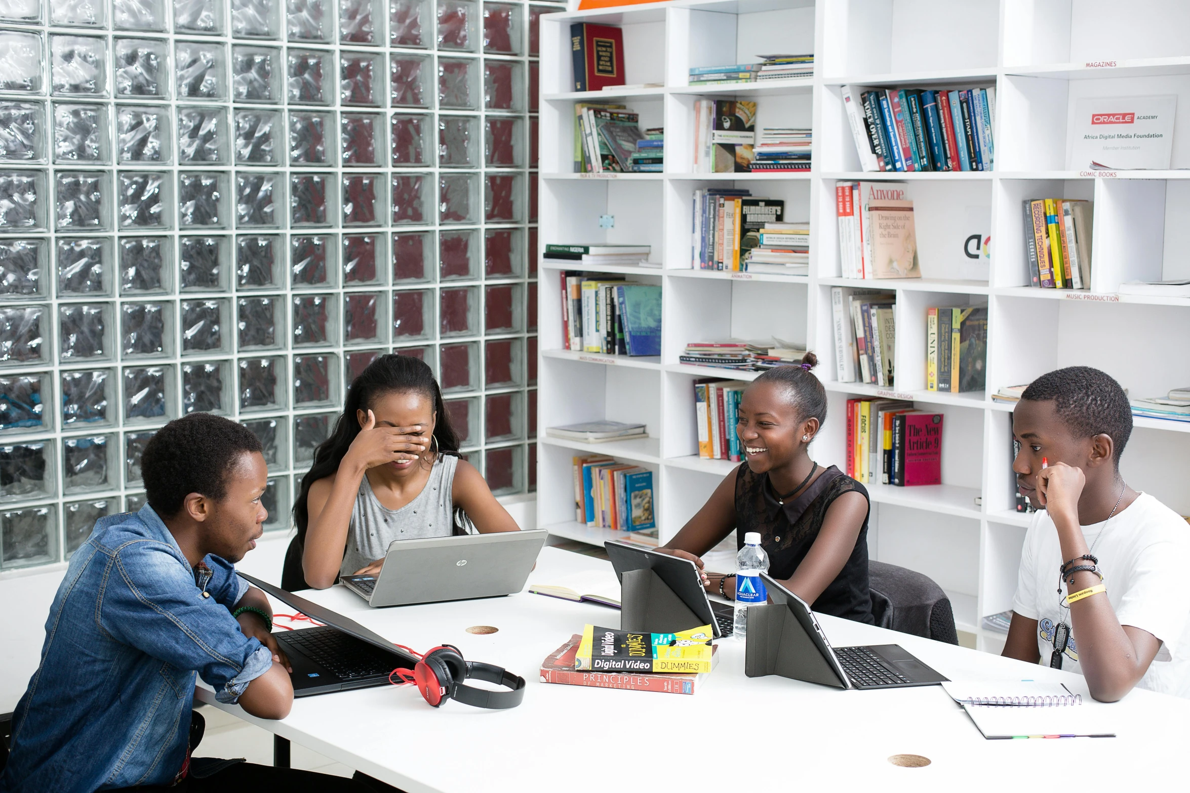 six young students at a white desk in front of glass blocks