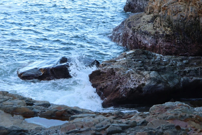 two large rocks near the ocean with a wave