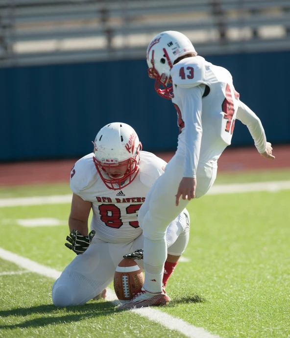 the two football players are attempting to catch the ball