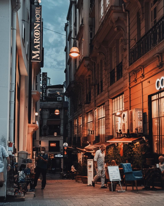 two people walking down a street with many buildings and signage