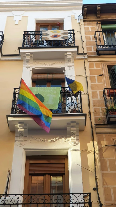a rainbow flag flies above the balcony of a building