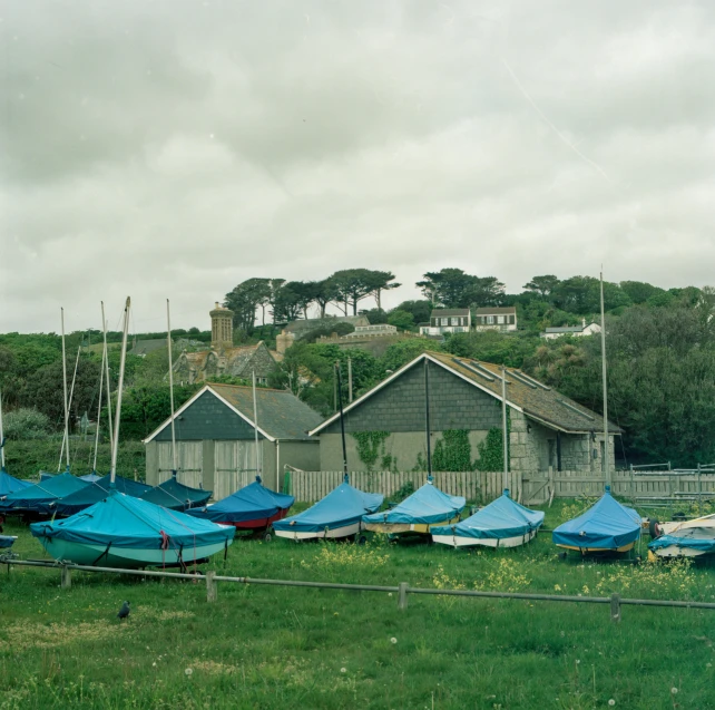 blue tents are sitting on the side of a grassy field